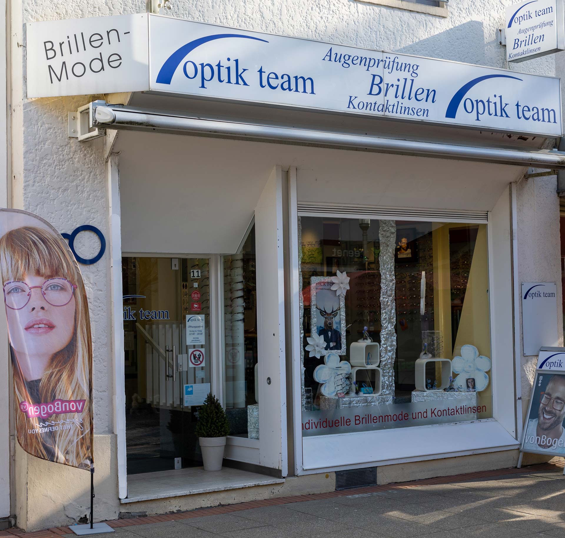 Ein Optikergeschäft mit einem Schaufenster voller Brillen und weißer Deko