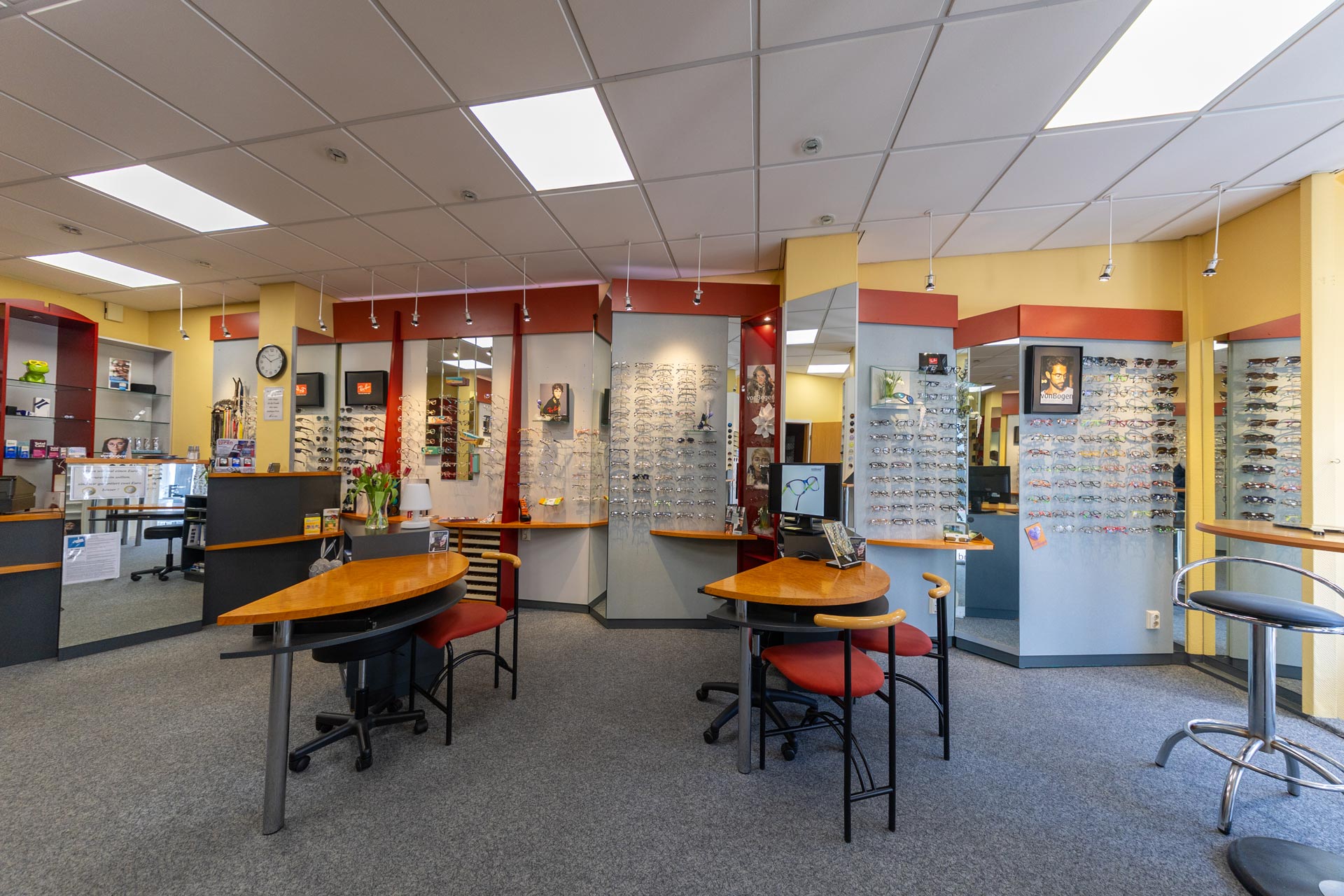 Ein freundliches Brillengeschäft mit modernen Holztischen und vielen ausgestellten Gestellen